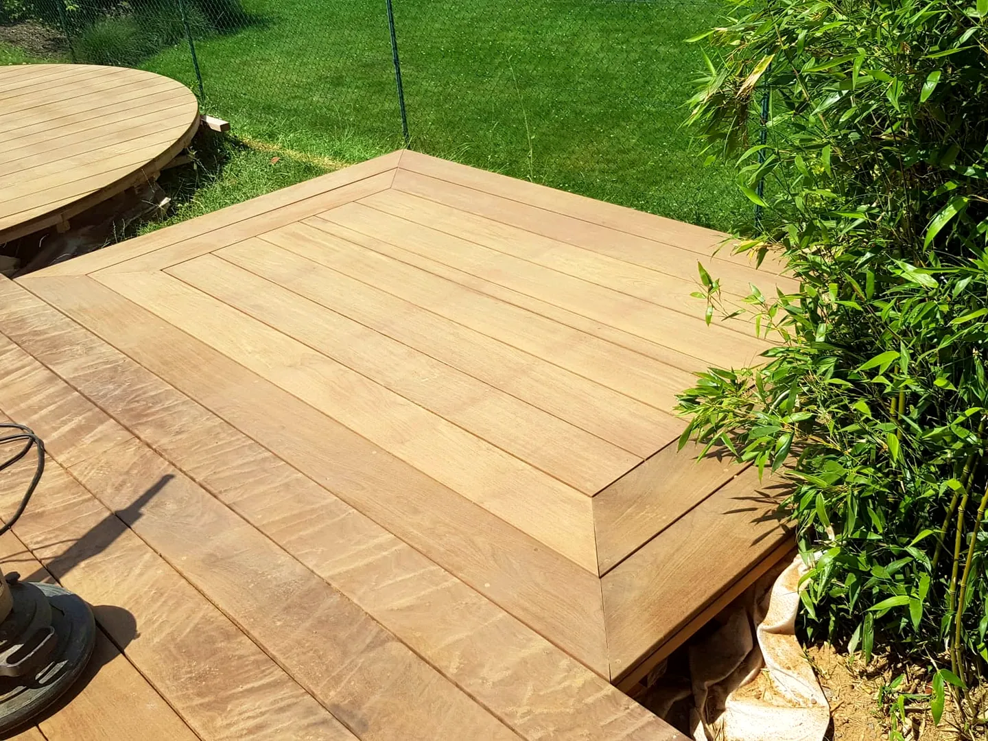 Terrasse ronde dessinée sur mesure dans un jardin, chantier Wood Floors en Belgique