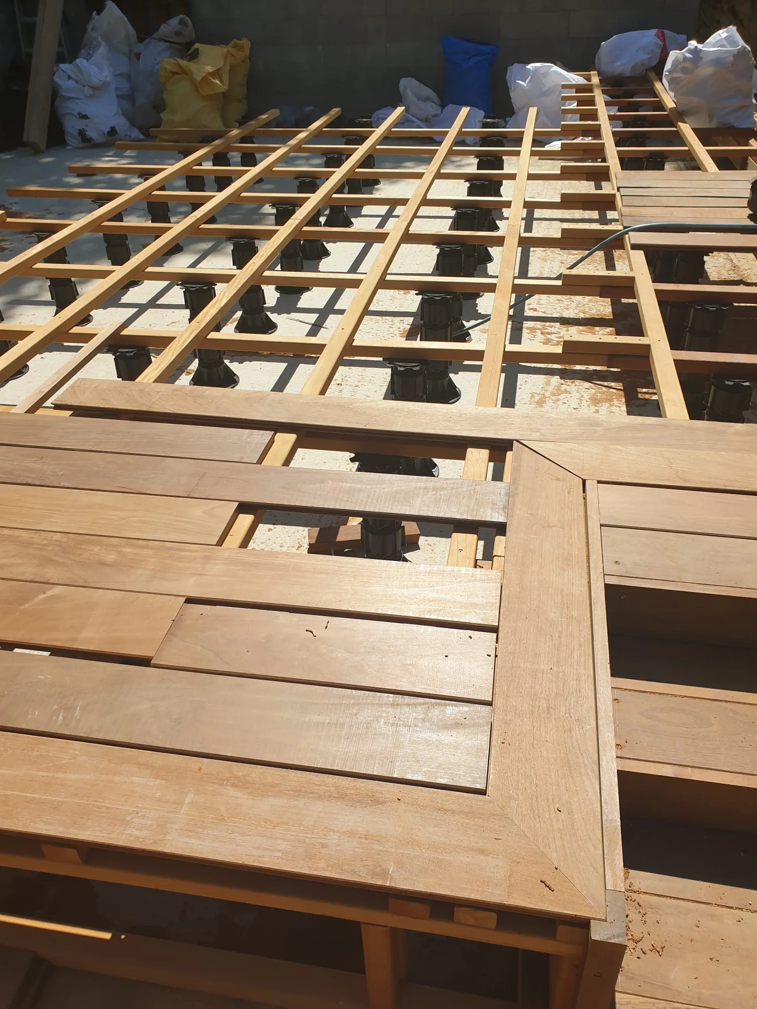 Lambourdes et premières lames de la terrasse en bois posées sur la structure, chantier Wood Floors